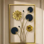 Metal wall art with gold flowers and navy blue lily pads in a gold rectangular frame